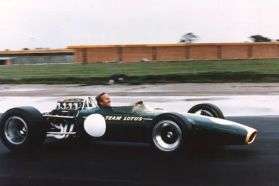 Colin Chapman stands beside the Lotus 49 Formula One car in 1967, the year it introduced the stressed-member engine concept that transformed F1 chassis design