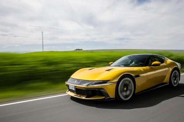 A yellow Ferrari 12Cilindri grand tourer, showing its fastback profile, long bonnet and rear-wheel-drive stance during a review.